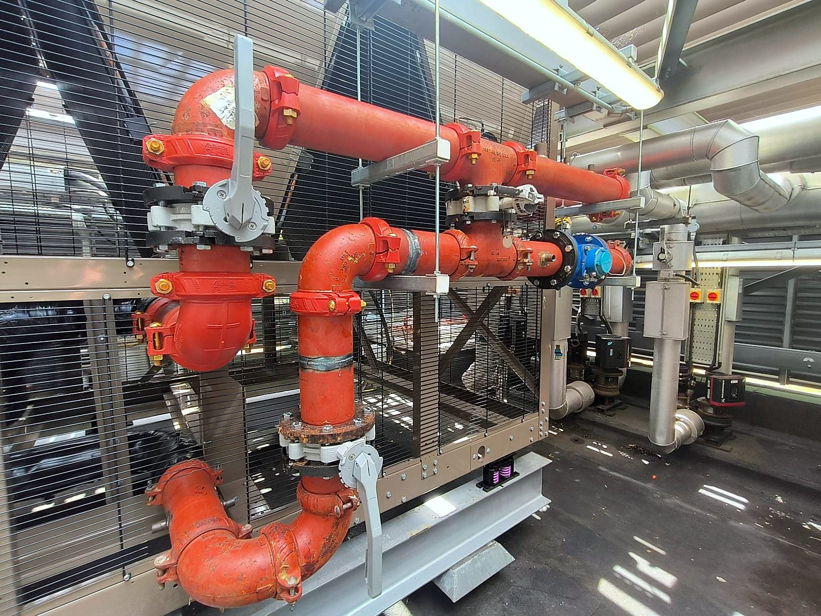 Red process pipework and valves on a rooftop cooling unit.